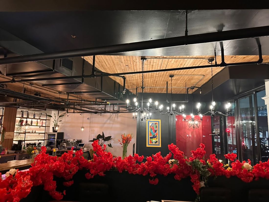 Les lustres à chandelles sous le plafond de bois, la salle fleurie de rouge et la porte laquée du bistro